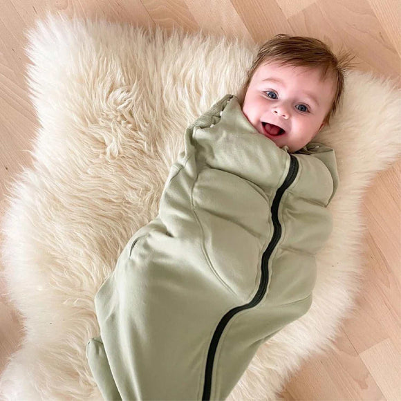 Baby in Tyngdeposen® Mini soothing sleeping bag on fluffy rug.